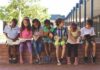 children sitting on a brick ledge reading books