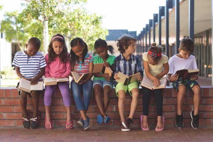 children sitting on a brick ledge reading books