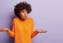 person shrugging in orange sweater against purple background