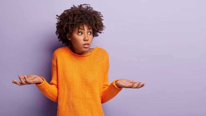 person shrugging in orange sweater against purple background