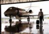 Kristi Noem’s Last-Day Deal Triggers Uproar Pilot walking with suitcase beside private jet in hangar