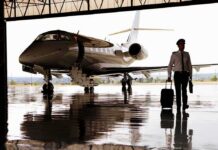 Pilot walking with suitcase beside private jet in hangar