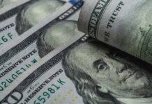 Backlash Erupts Over Immigrant Stipends U.S. 100-dollar bills with one note rolled over Benjamin Franklin portrait