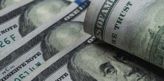 U.S. 100-dollar bills with one note rolled over Benjamin Franklin portrait