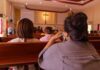 Durham Smudging Uproar – Pagan Rite Panic Hits Catholic Parish people seated in church pews facing a cross
