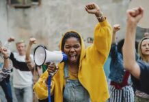 Protester in yellow hoodie shouting into a megaphone