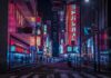 Night city street with neon signs and blurred pedestrians