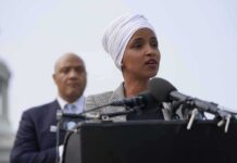 FBI Rule-Break Raid? Omar Lawyers Cry Foul Ilhan Omar speaking at a podium with André Carson standing behind