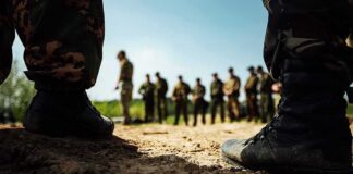 Soldiers in boots framing a group standing in a field