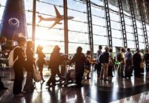 Roads Over Runways: Gulf Travelers Bolt Passengers queue inside an airport terminal at sunset