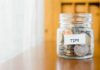 Governor Veto Halts Paycheck Savings Tip jar filled with assorted coins on a wooden counter