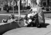 Man sleeping on park ledge beside overloaded cart