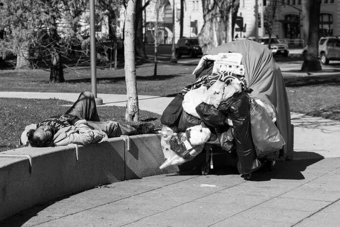 Man sleeping on park ledge beside overloaded cart
