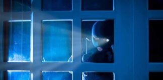Masked intruder peering through a window at night