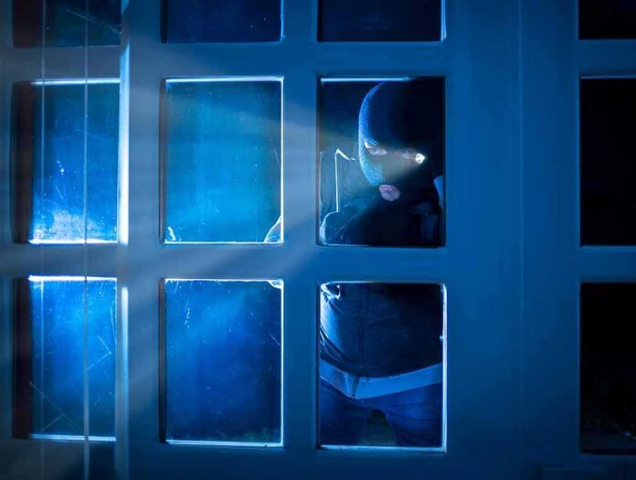 Masked intruder peering through a window at night
