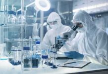 Scientists in protective suits using a microscope in a laboratory