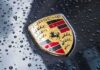 Luxury Squeeze: Porsche Cuts, Charges More Porsche crest on wet car hood