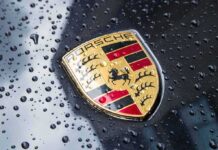 Luxury Squeeze: Porsche Cuts, Charges More Porsche crest on wet car hood